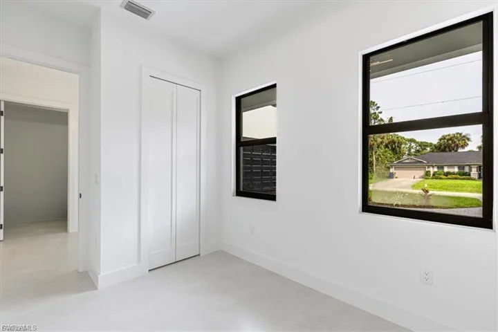 White walls with crisp baseboards, light-toned flooring, and two modern black-framed windows