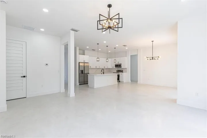 Open-concept living area with light-toned flooring, recessed lighting, and modern chandeliers