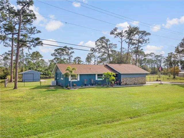 View of front of home with a front yard and an outdoor structure