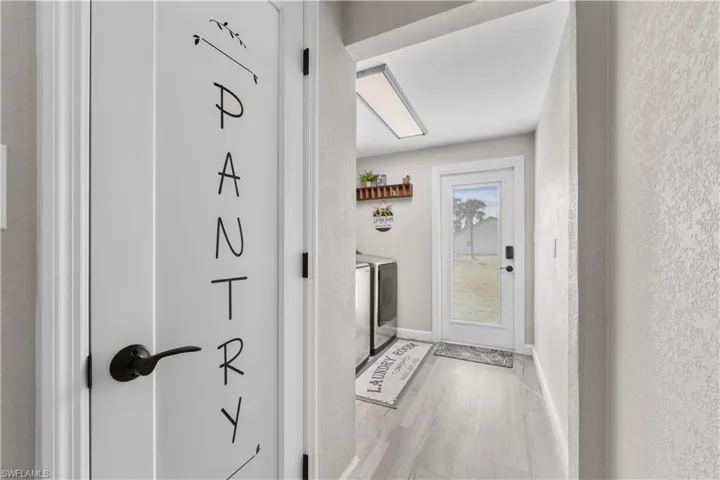 Doorway with light wood-type flooring and independent washer and dryer