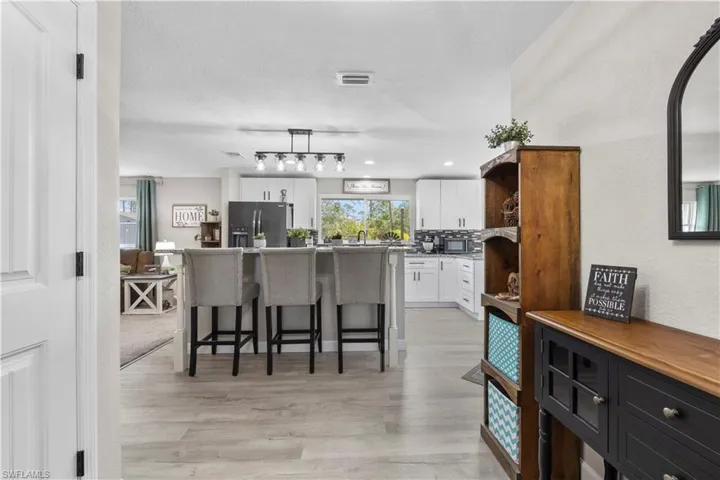Kitchen with a center island, stainless steel fridge with ice dispenser, white cabinetry, a kitchen breakfast bar, and backsplash