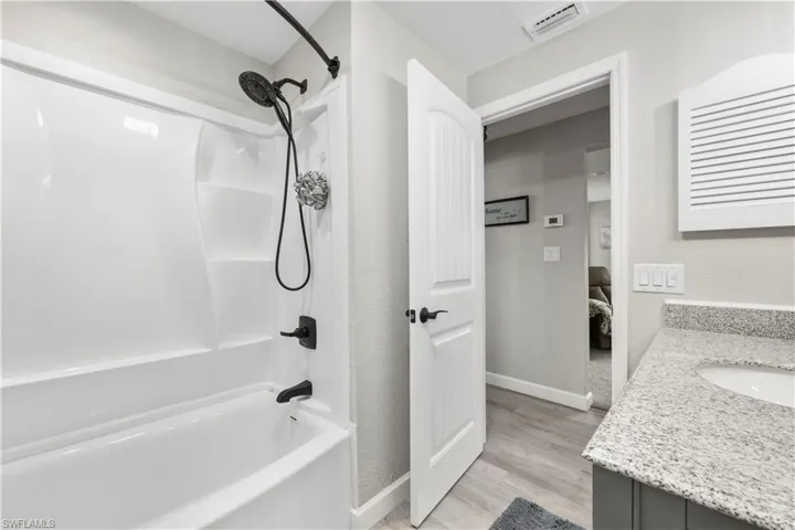 Bathroom featuring vanity, hardwood / wood-style flooring, and shower / washtub combination