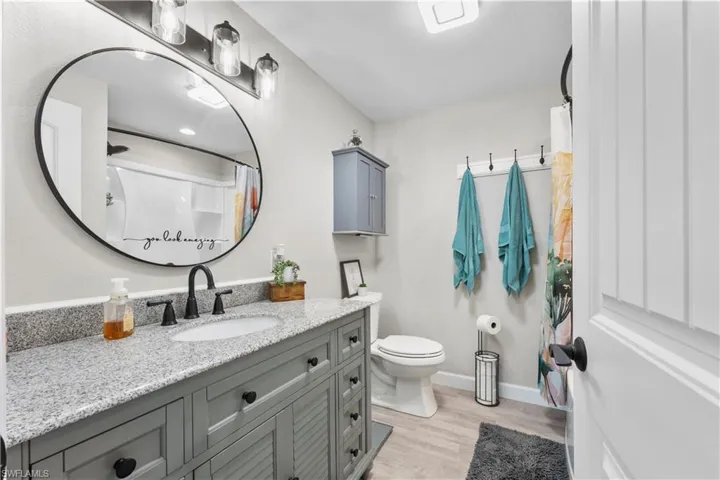 Bathroom with hardwood / wood-style floors, toilet, walk in shower, and vanity