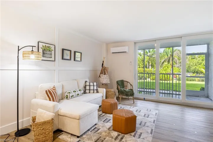 Living area featuring wood finished floors, a wall unit AC, a wall of windows, and crown molding