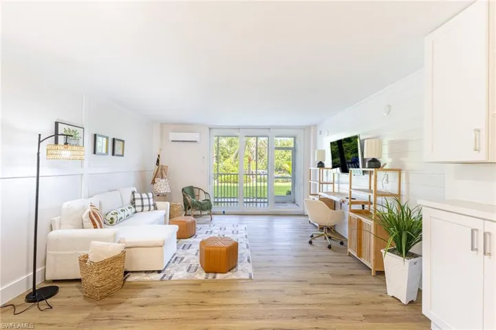 Living room featuring light wood-style floors, crown molding, and a wall mounted air conditioner