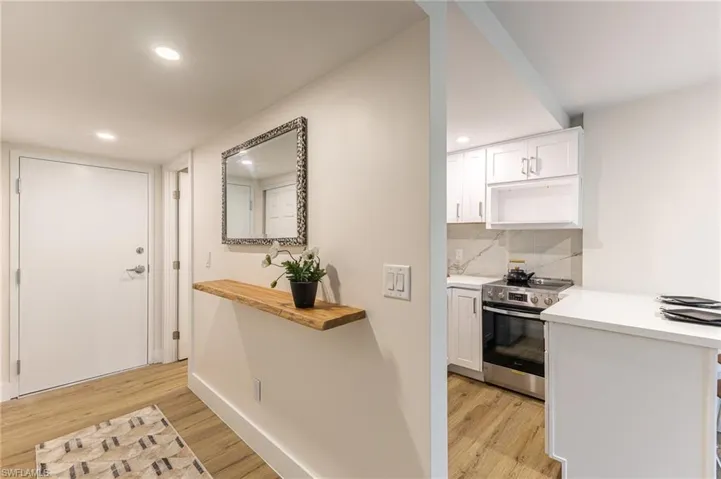 Kitchen featuring stainless steel range with electric cooktop, white cabinets, light wood-type flooring, and recessed lighting