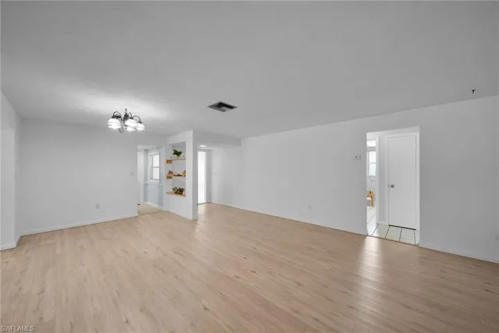 Unfurnished living room featuring light wood-type flooring and a chandelier