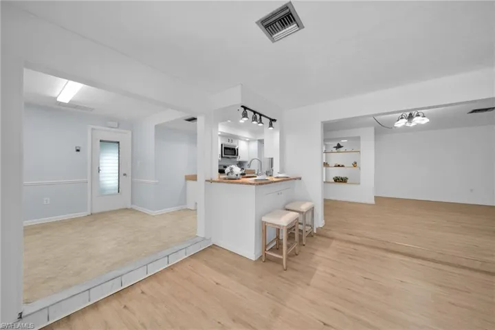 Kitchen with light wood finished floors, a breakfast bar, open floor plan, a chandelier, and appliances with stainless steel finishes