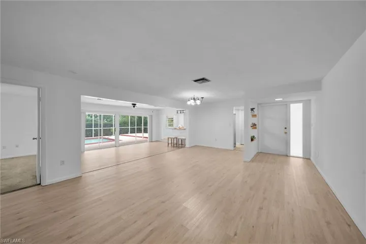 Unfurnished living room featuring light wood-type flooring and a chandelier