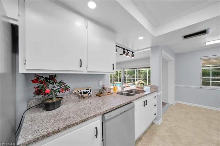 Kitchen with white cabinetry, dishwasher, light stone counters, plenty of natural light, and recessed lighting
