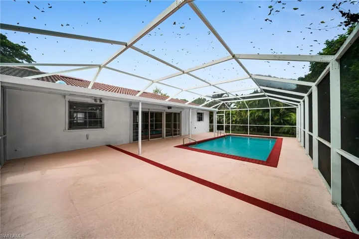 Outdoor pool featuring a sunroom, a patio area, and glass enclosure