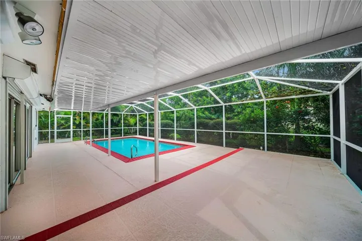 Outdoor pool with a sunroom, glass enclosure, and a patio