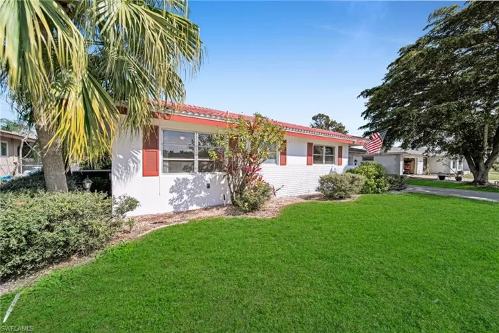 View of front of property featuring stucco siding, a front yard, and a tile roof