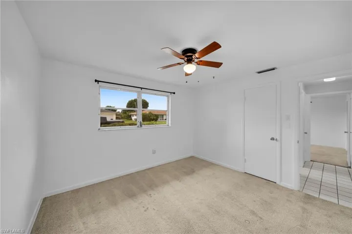 Unfurnished bedroom with light carpet and a ceiling fan