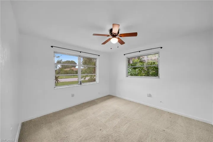 Spare room with healthy amount of natural light, light carpet, and a ceiling fan