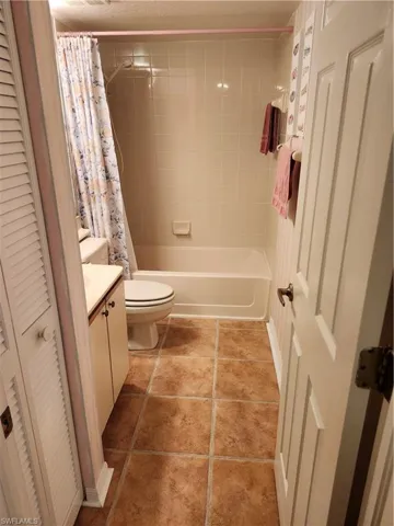 Full bathroom featuring tile patterned floors, toilet, shower / tub combo with curtain, and vanity