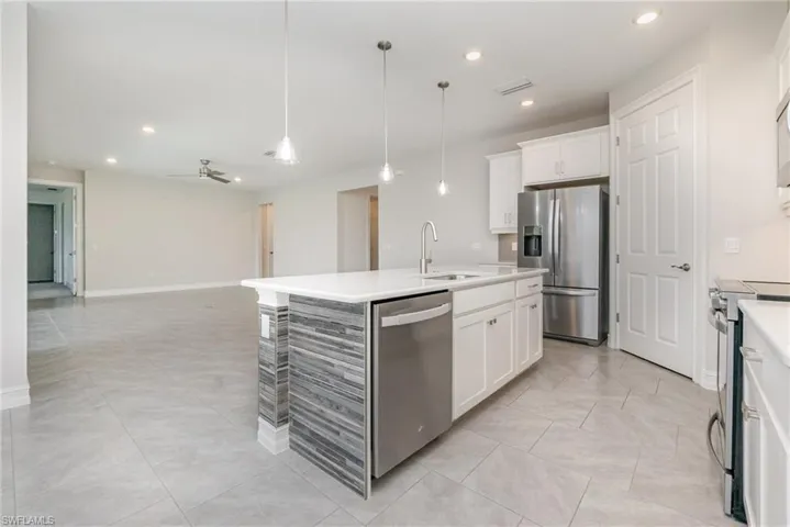Kitchen with pendant lighting, appliances with stainless steel finishes, recessed lighting, open floor plan, and white cabinets