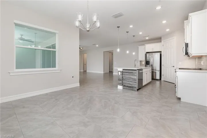 Kitchen with a breakfast bar area, pendant lighting, open floor plan, white cabinets, and recessed lighting