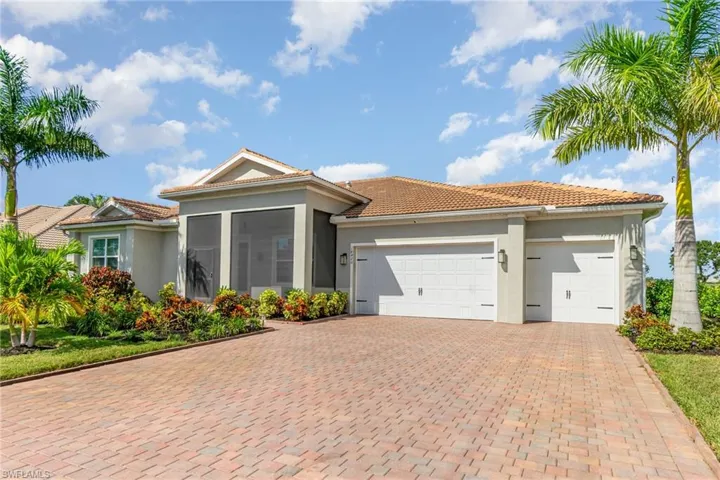 View of front of home featuring an attached garage, stucco siding, a sunroom, decorative driveway, and a tile roof