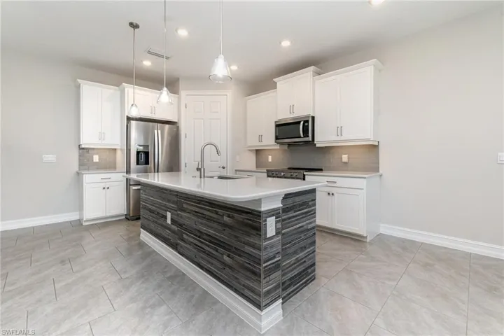 Kitchen with backsplash, white cabinets, a kitchen island with sink, stainless steel appliances, and recessed lighting