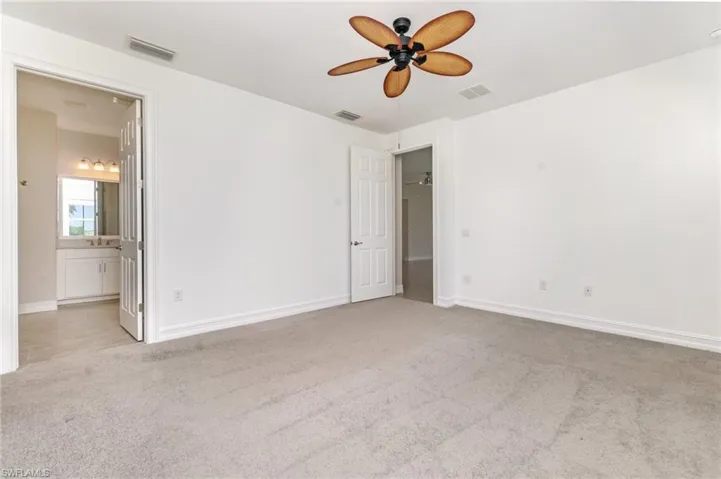 Unfurnished bedroom with light carpet, a ceiling fan, and ensuite bathroom