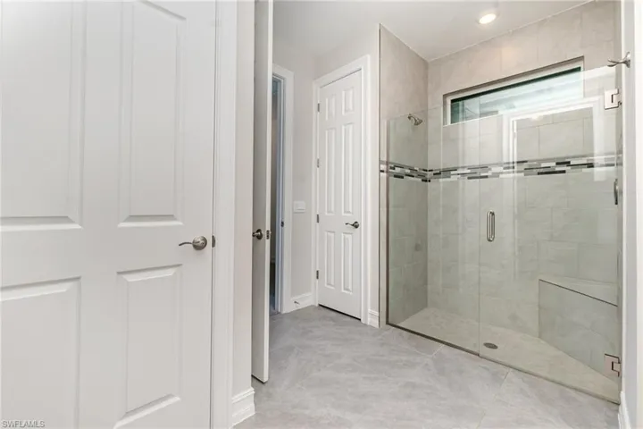 Bathroom with a shower stall and light tile patterned flooring