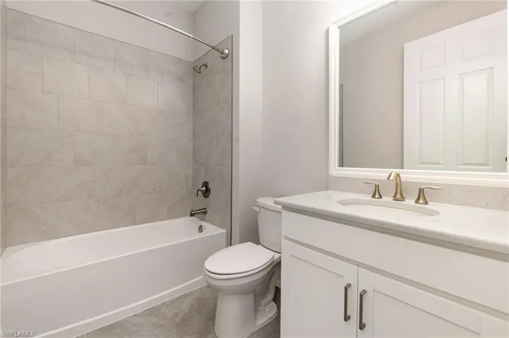 Bathroom with vanity, bathing tub / shower combination, and light tile patterned floors