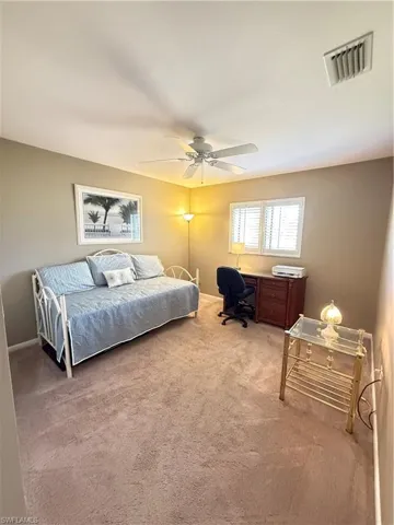 Bedroom with a desk, light colored carpet, and ceiling fan