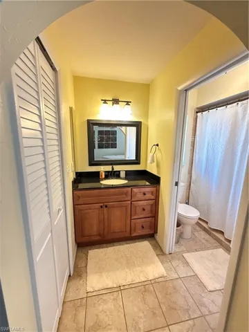 Full bath featuring vanity, curtained shower, and a closet