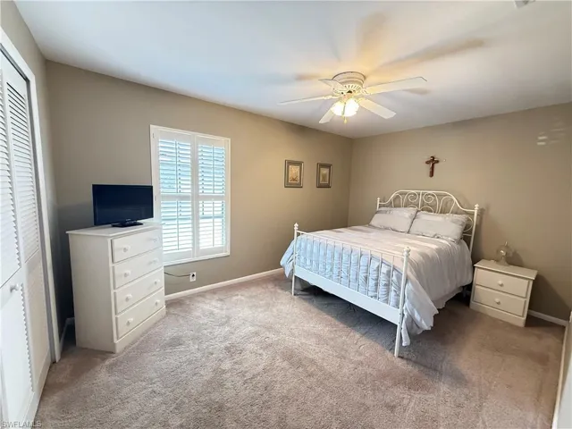 Bedroom with ceiling fan, light carpet, and a closet