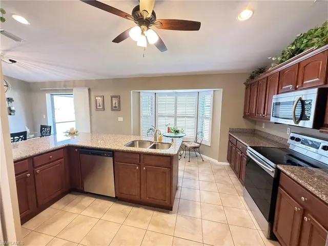 Kitchen with stainless steel appliances, recessed lighting, ceiling fan, light stone counters, and light tile patterned floors