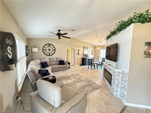 Living area with vaulted ceiling, light tile patterned flooring, and ceiling fan
