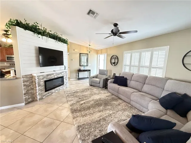 Living area featuring ceiling fan, light tile patterned floors, and a fireplace