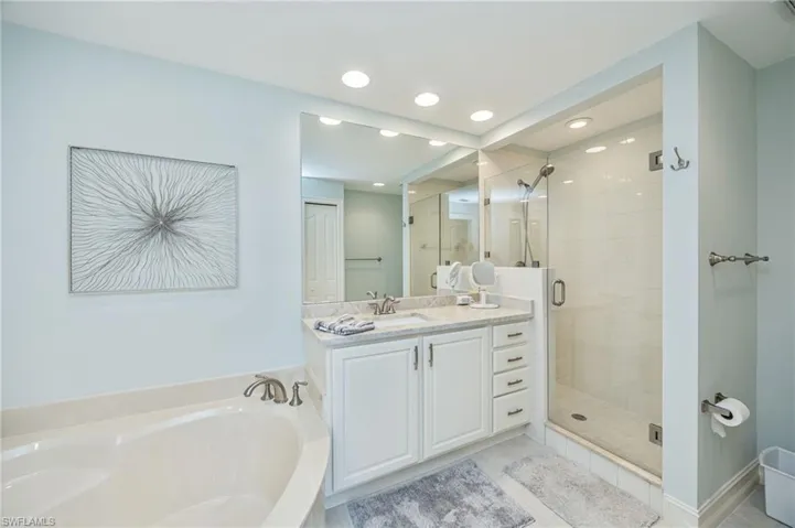 Bathroom with a stall shower, vanity, a garden tub, and recessed lighting