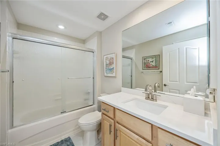 Bathroom featuring vanity, combined bath / shower with glass door, light tile patterned floors, and recessed lighting