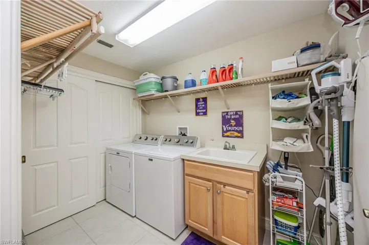 Laundry room with washing machine and dryer, cabinet space, and light tile patterned flooring