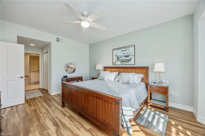 Bedroom featuring light wood-style floors, a closet, a ceiling fan, and ensuite bath