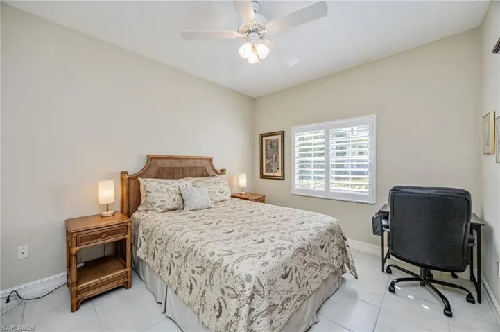 Bedroom featuring ceiling fan, light tile patterned floors, and an office area