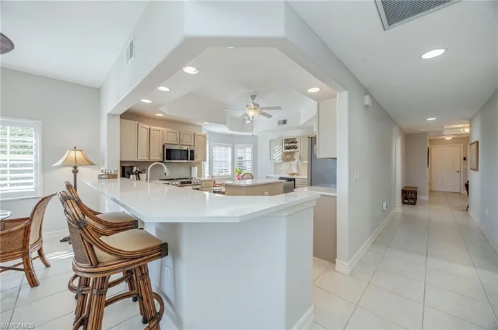 Kitchen with a kitchen island, light tile patterned flooring, a raised ceiling, stainless steel appliances, and a peninsula