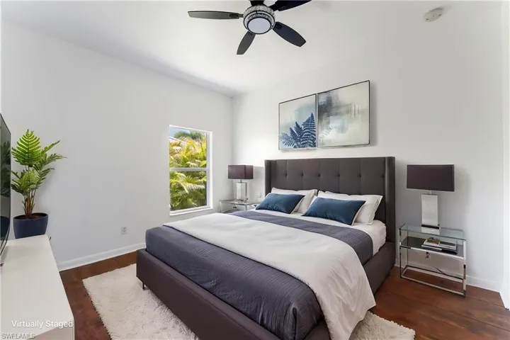 Bedroom featuring wood-finish flooring, a ceiling fan, and a window offering abundant natural light
