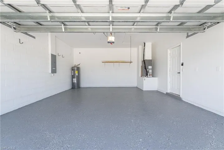 Spacious garage featuring a durable speckled epoxy floor, white painted block walls, and an accessible side entrance