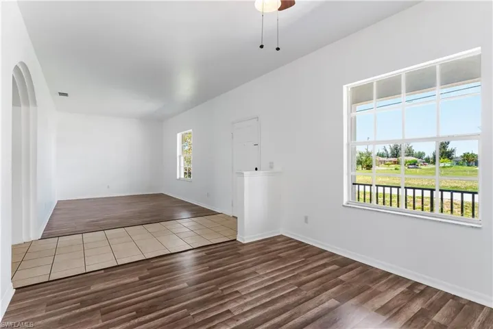 Bright interior space featuring wood-finish flooring, a large window with white grid panes, and a contemporary ceiling fan with light fixture