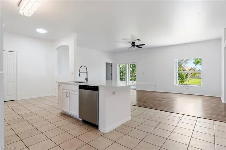 Kitchen island featuring a stainless steel sink with a high-arc faucet, integrated dishwasher, and white cabinetry