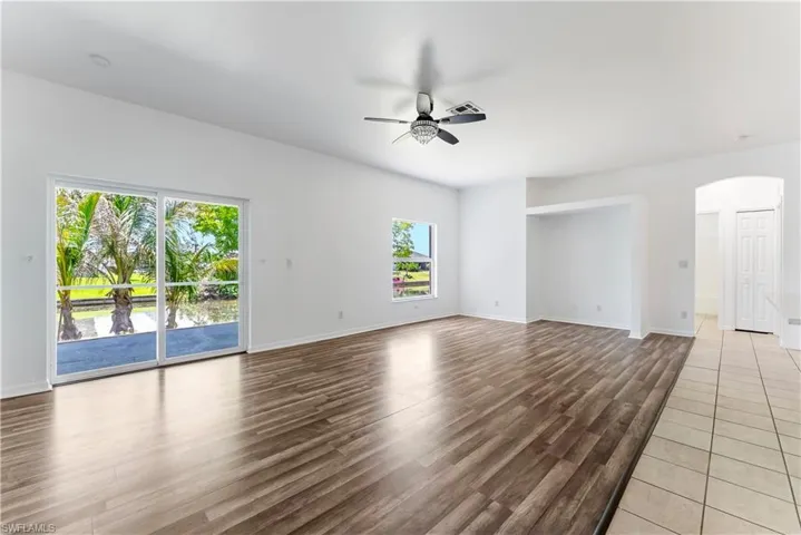 Spacious interior featuring wood-finish flooring, white walls, and a ceiling fan with light fixture