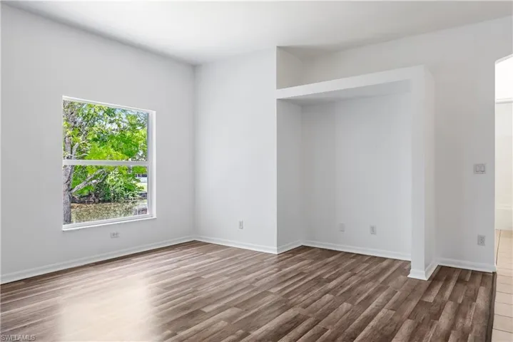 Spacious room featuring wood-finish flooring, a large window, and a built-in architectural niche