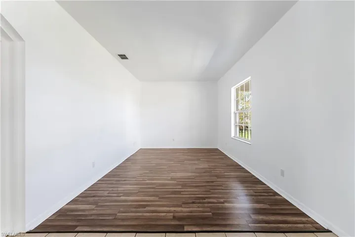 Spacious room featuring wood-finish flooring and neutral white walls