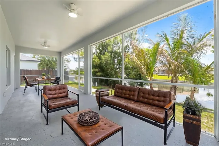 STAGED Screened patio featuring a solid ceiling with two flush-mount ceiling fans, concrete flooring, and distant water views