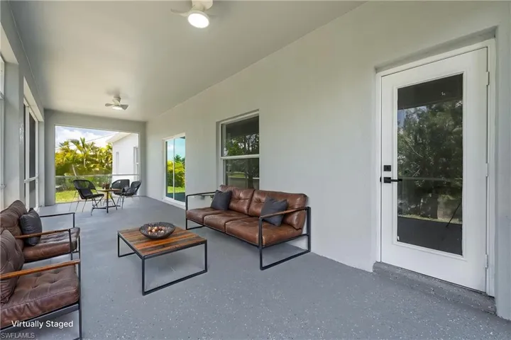 STAGED spacious covered patio featuring a full-light entry door, multiple windows, two ceiling fans, and a speckled gray flooring finish
