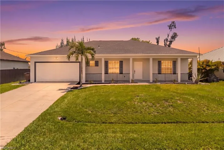 Modern single-story residence featuring a two-car garage, covered entry porch with black railings, and a concrete driveway