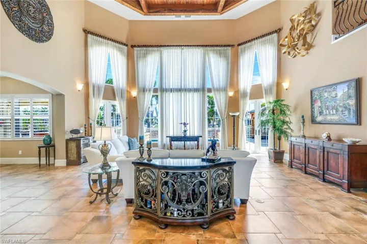 Living room with a high ceiling, a raised ceiling, and light tile floors